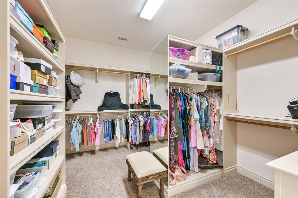 Spacious walk-in closet with ample shelving, hanging space, perfect for organizing clothes and accessories.