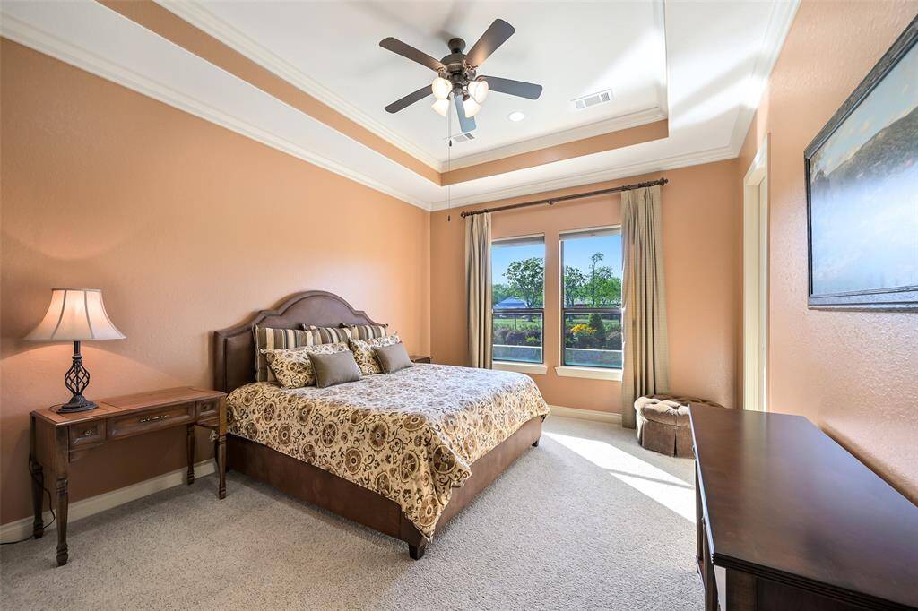 This second primary bedroom features warm terracotta walls, a tray ceiling, and large windows that provide ample natural light. Attached en-suite bathroom and walk in closet make for a perfect guest suite.