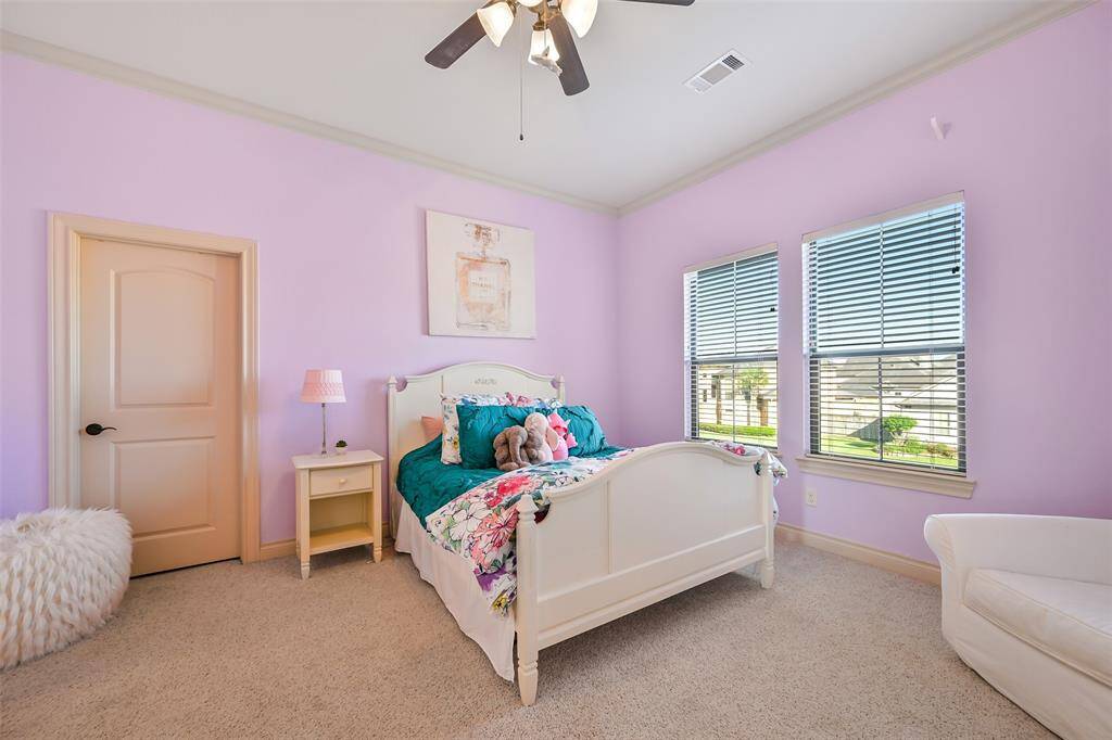 This photo showcases a cozy bedroom with ample natural light from two large windows. It features a private full bathroom and walk in closet.