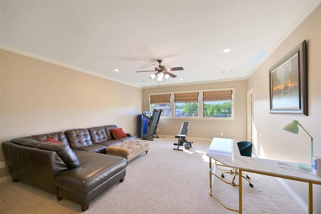 Spacious game room features natural light through multiple windows, attached half bath and large walk in storage closet highlighting the versatile layout ideal for relaxation or work.