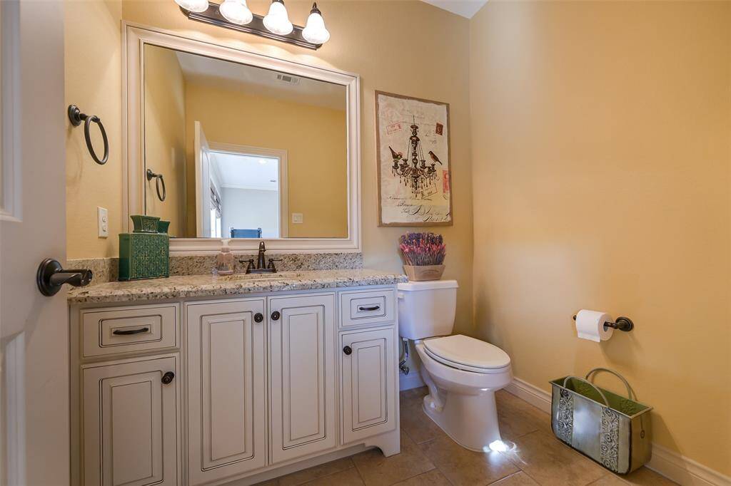 This half bathroom features a granite countertop, and a classic white vanity with ample storage attached to the game room.