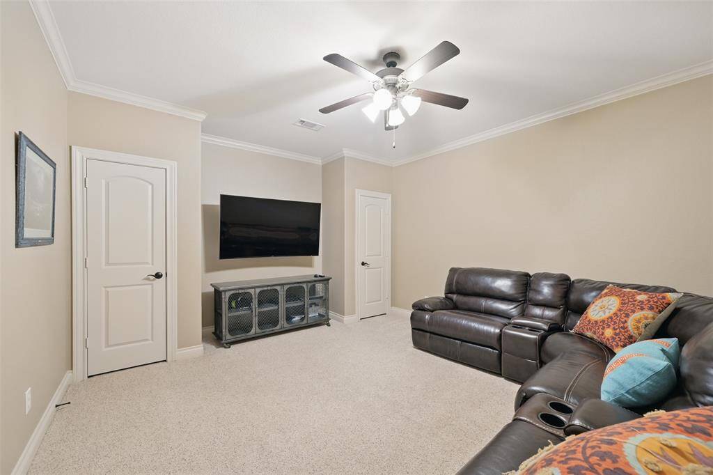 Cozy media room with neutral walls, featuring a large TV area and two closets with built in shelves. Great for movie watching and entertainment.
