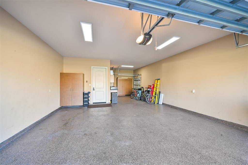 Spacious garage with epoxy floor, multiple built-in storage spaces, and ample room for parking and organizing tools or outdoor gear.