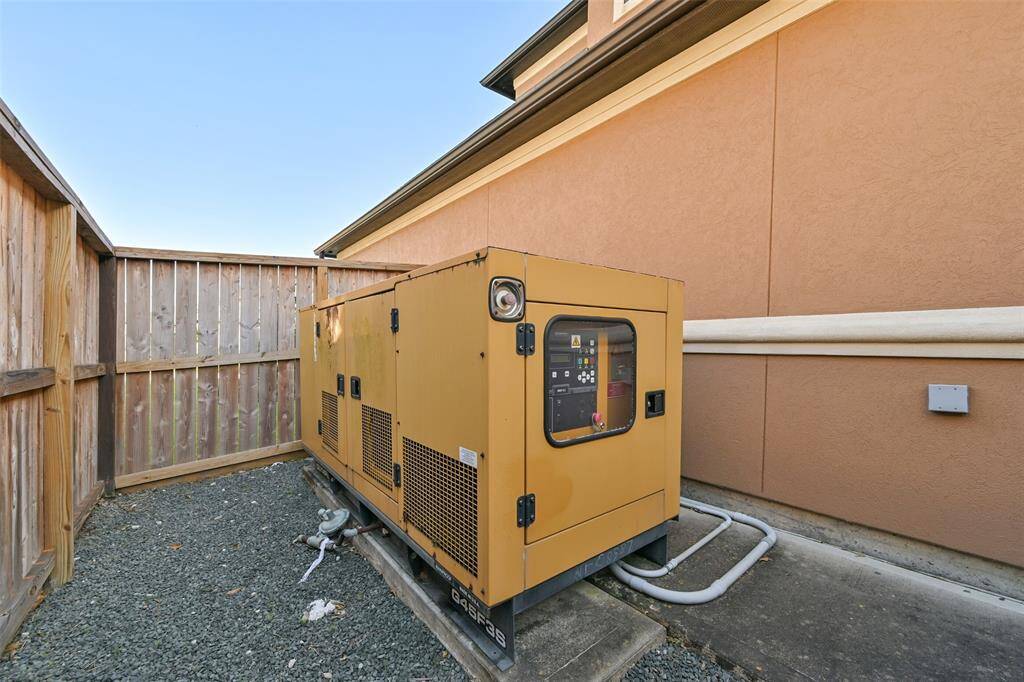 A large Olympian generator situated next to a house, enclosed by a fence, providing backup power capability for the property.