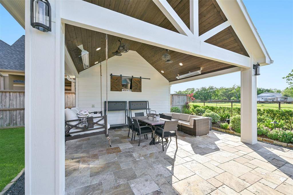 A large covered pavilion with a vaulted cedar ceiling with attached heaters and bluetooth speakers. It features a built in TV space and a sofa swing, perfect for entertaining.