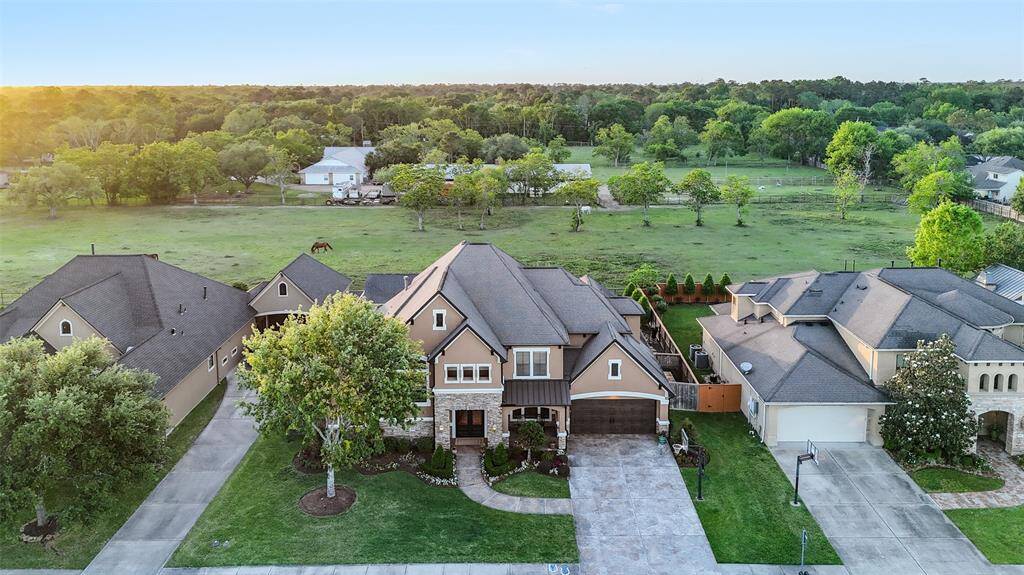 The property is set in a serene neighborhood with lush greenery and open fields behind, offering a peaceful, picturesque setting.