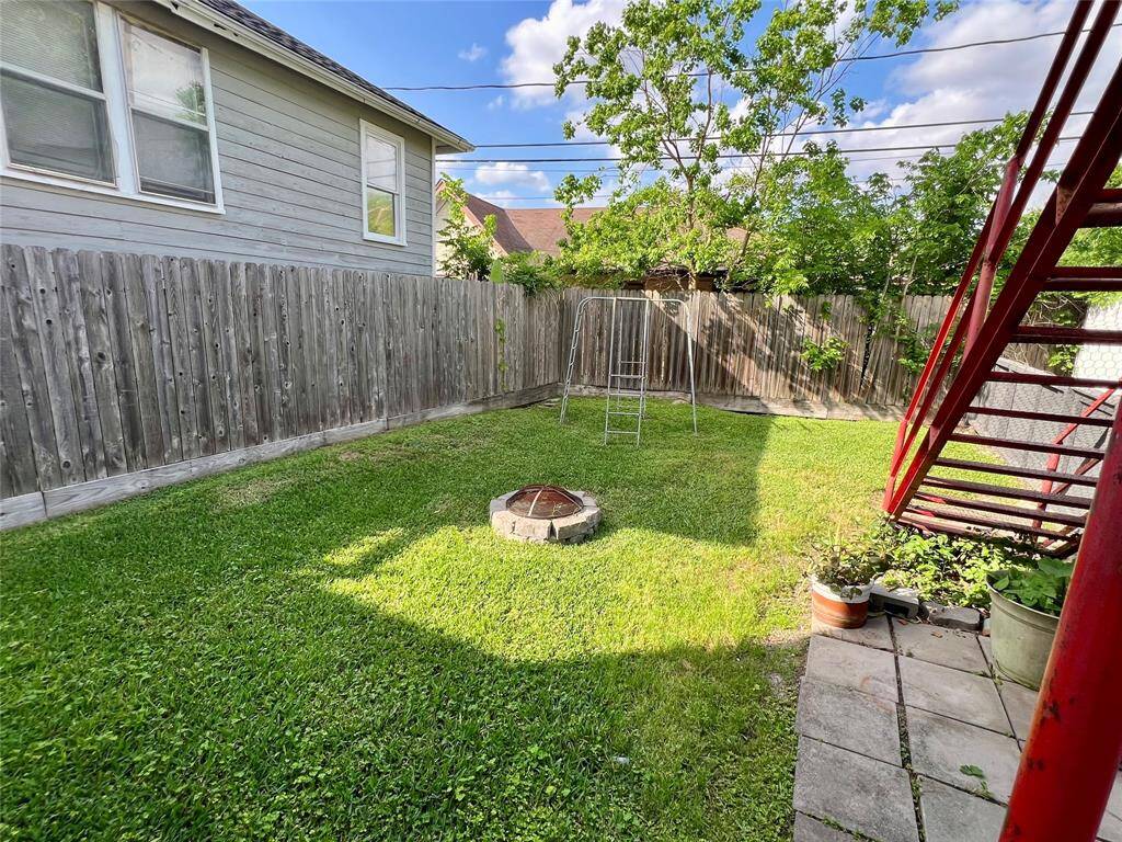 The fully fenced backyard has a beautiful lawn with a fire pit and playscape area.