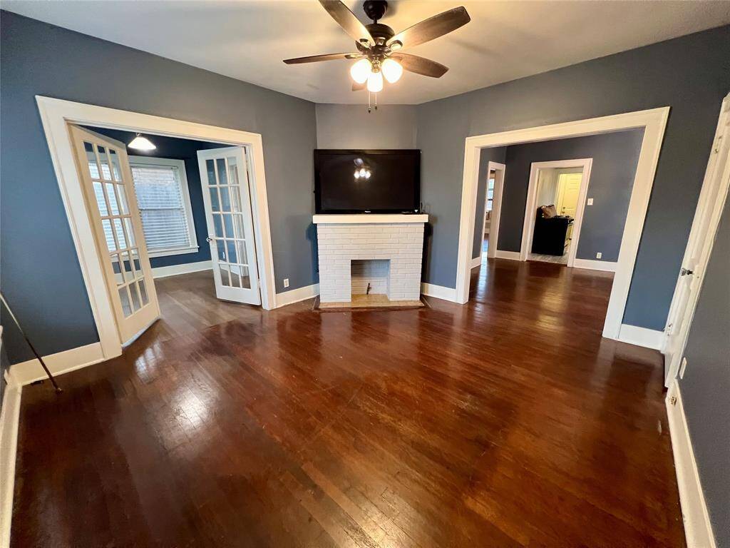The living room has hardwood floors and a mock fireplace accent. French Doors lead to the extra room and the dining room is on the right. There is also access to a large storage closet.