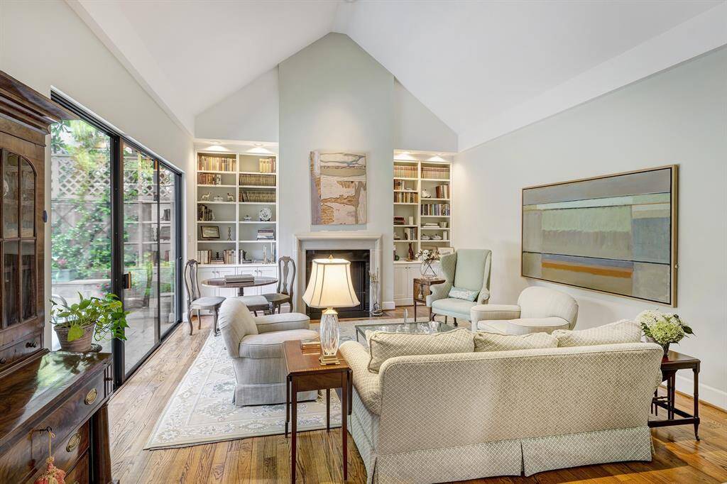 The soaring cathedral ceiling in the living room adds flair. The woodburning fireplace is flanked by shelves and cabinets for display and storage.