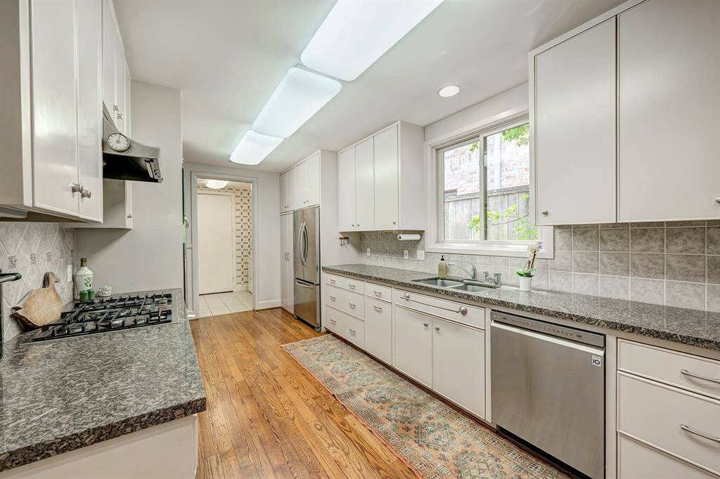 The efficient kitchen has long granite counters and lots of great storage.  Beyond is the large utility room/mud room with numerous drawers and cabinets and large stainless utility sink and access to the oversized garage with additional counters, drawers and cabinets.