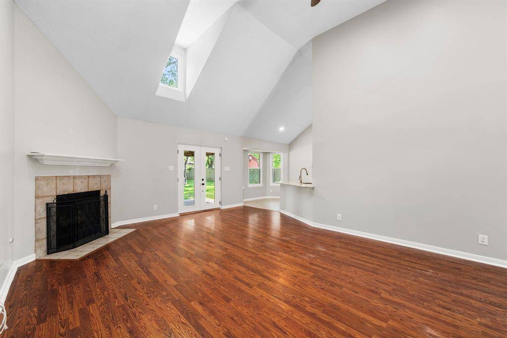 This spacious living area features high vaulted ceilings, a cozy fireplace, and convenient view into the kitchen. Access to the backyard is through elegant double doors.