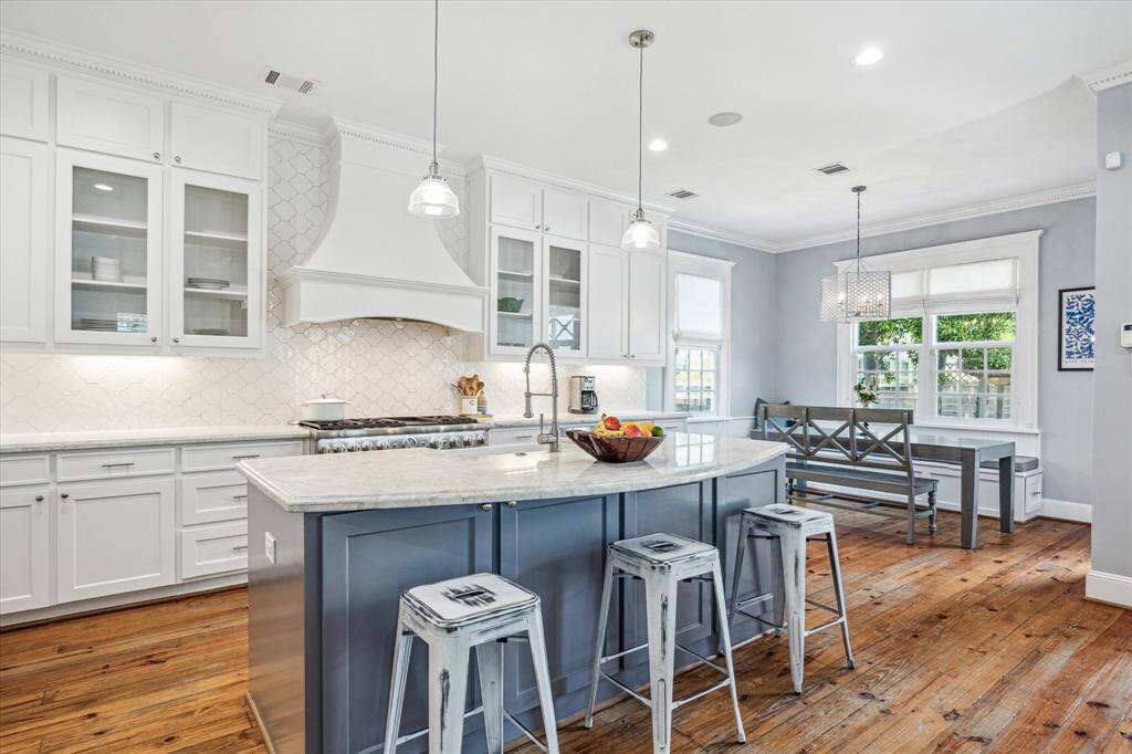 A chef’s dream, the kitchen features crisp white cabinetry, quartzite countertops, and a large center island with bar seating.