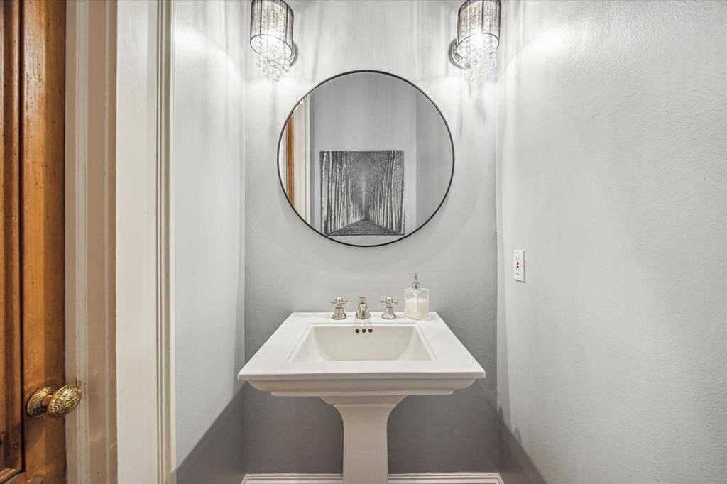 This elegant powder room features a classic pedestal sink and sconce lighting.