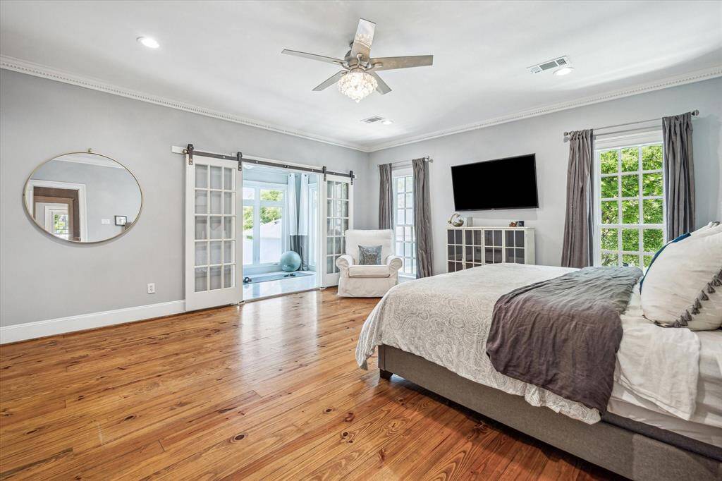 The spacious primary suite is a serene retreat with warm hardwood floors, elegant crown molding, and amplenatural light.
