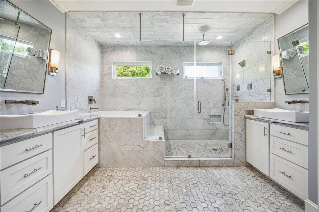 A luxurious spa-like experience awaits in this marble-clad primary bathroom.