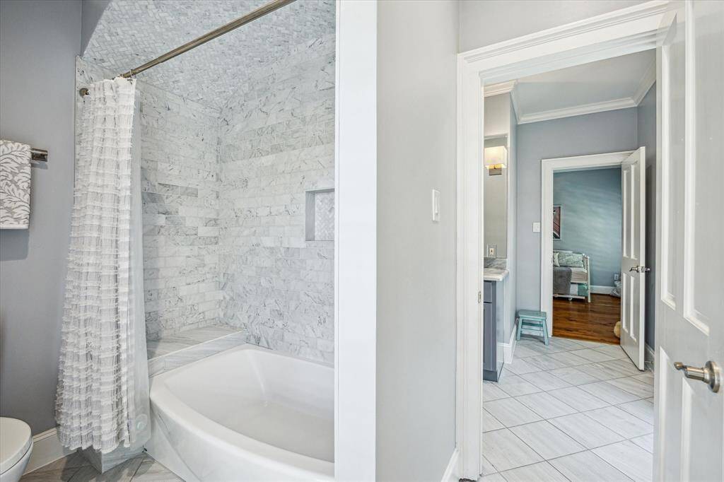The shared full bath is thoughtfully designed with a double vanity topped in marble, ample storage, and elegant tile flooring.