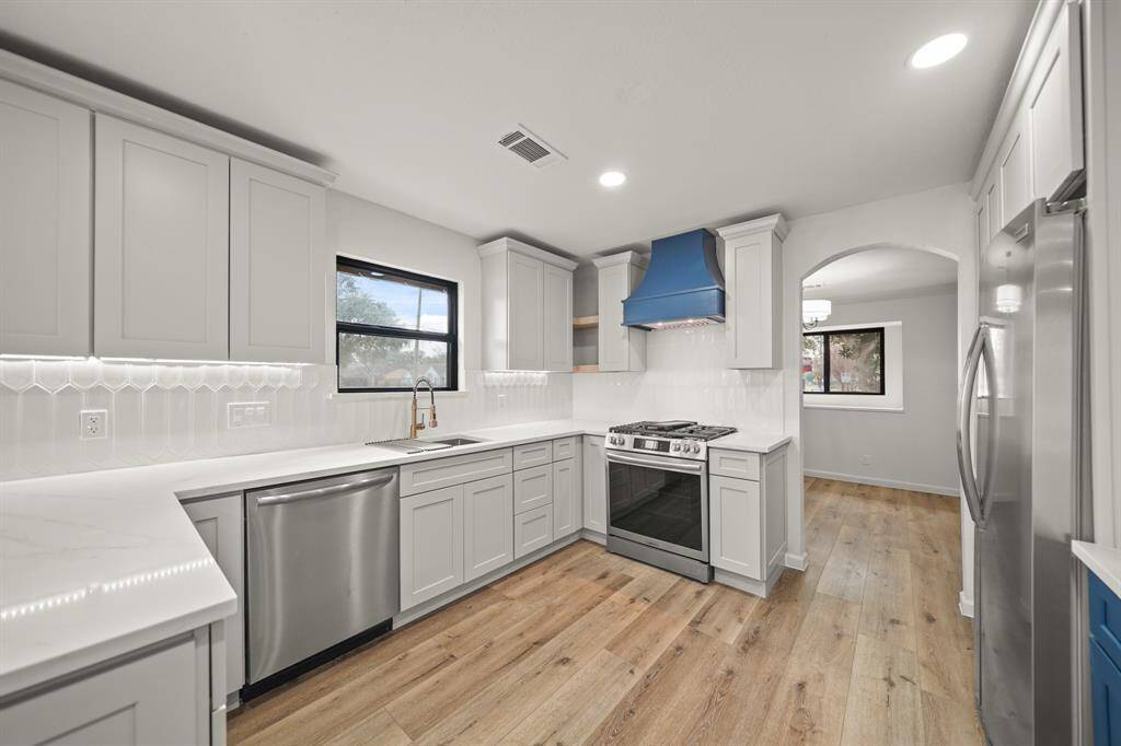 The white cabinetry paired with a striking blue range hood creates a fresh and sophisticated color combination.