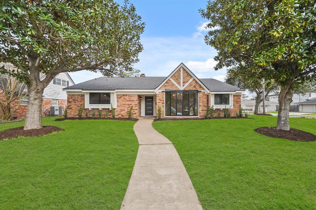 The lush green front yard with mature trees adds a touch of serenity.