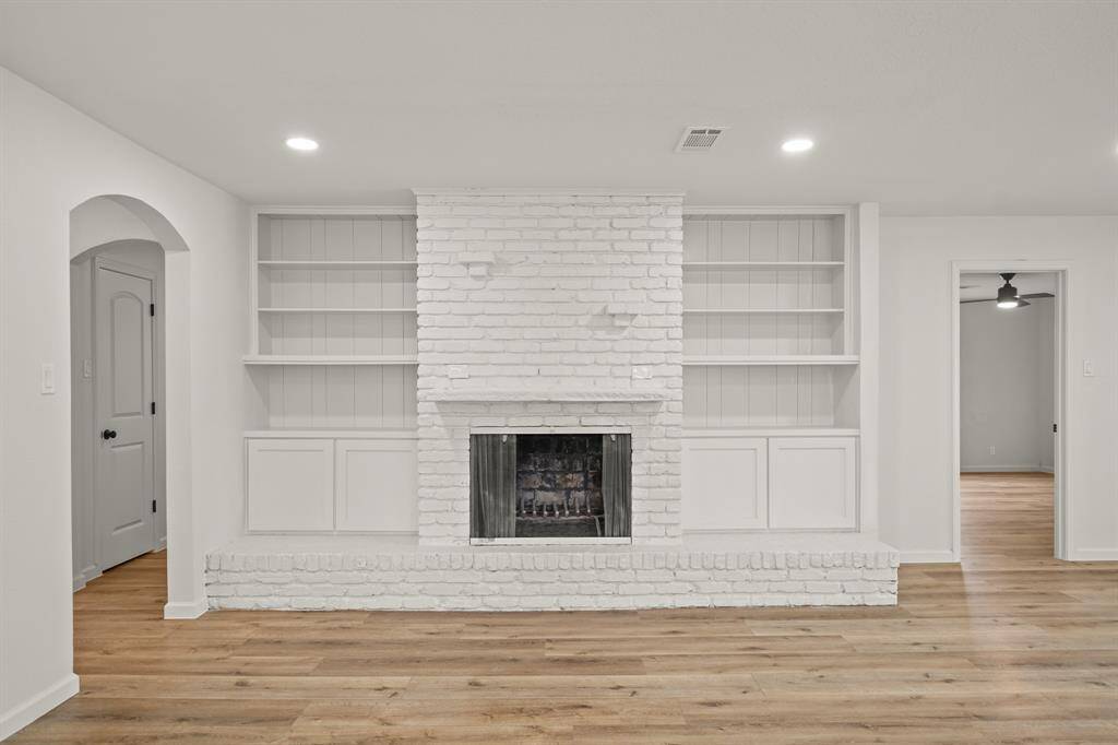 Family room is highlighted by a beautiful white brick fireplace with built-in shelves and cabinets on the side, adding a cozy yet modern touch to the room.