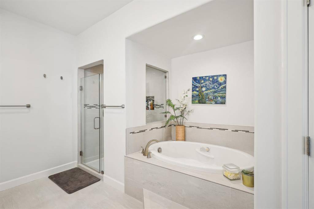 Walk-in shower and a spacious bathtub. It's adorned with neutral tiles creating a serene and inviting atmosphere.