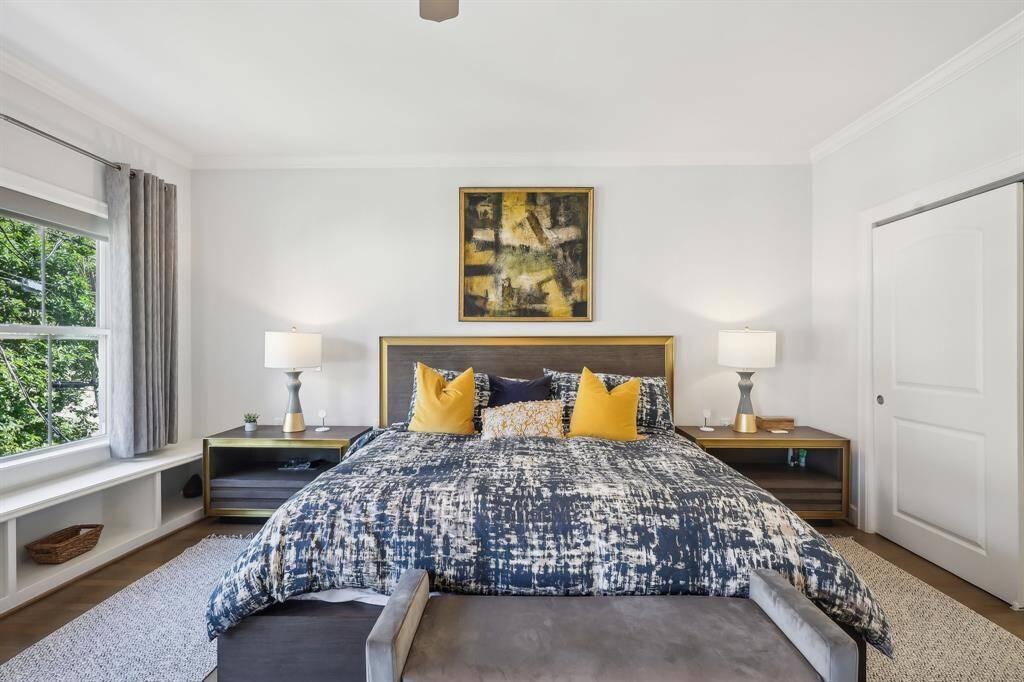 The primary bedroom is bright and inviting and has built-in shelving beneath the windows.
