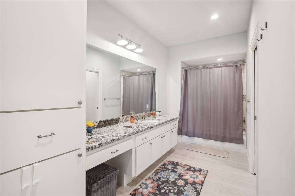 Upstairs hall bathroom features a spacious double vanity with granite countertops, ample storage, and a modern design. It has a neutral color scheme, recessed lighting, and a tub-shower, perfect for a clean and functional space.