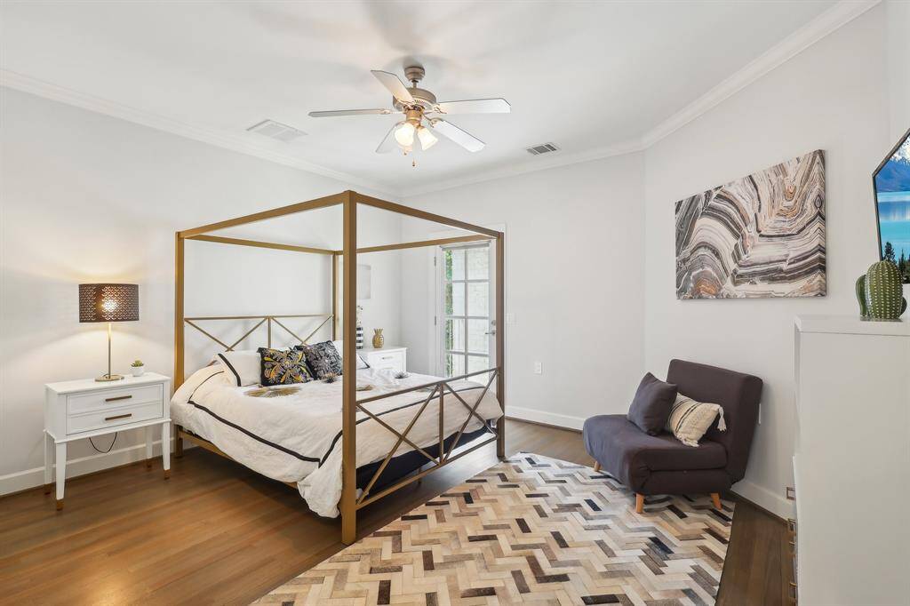 Bright and inviting bedroom with hardwood floors, ceiling fan, and private balcony.