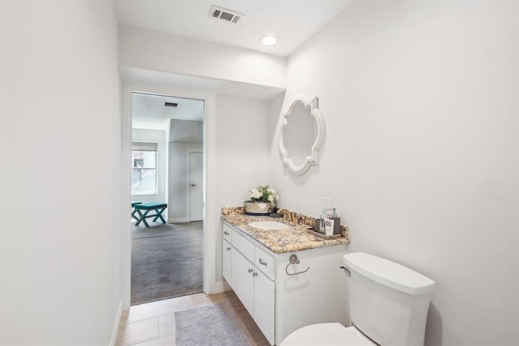 This third floor bathroom shows a has granite countertop, white cabinetry, and a stylish mirror. It has space and plumbing for an additional shower.