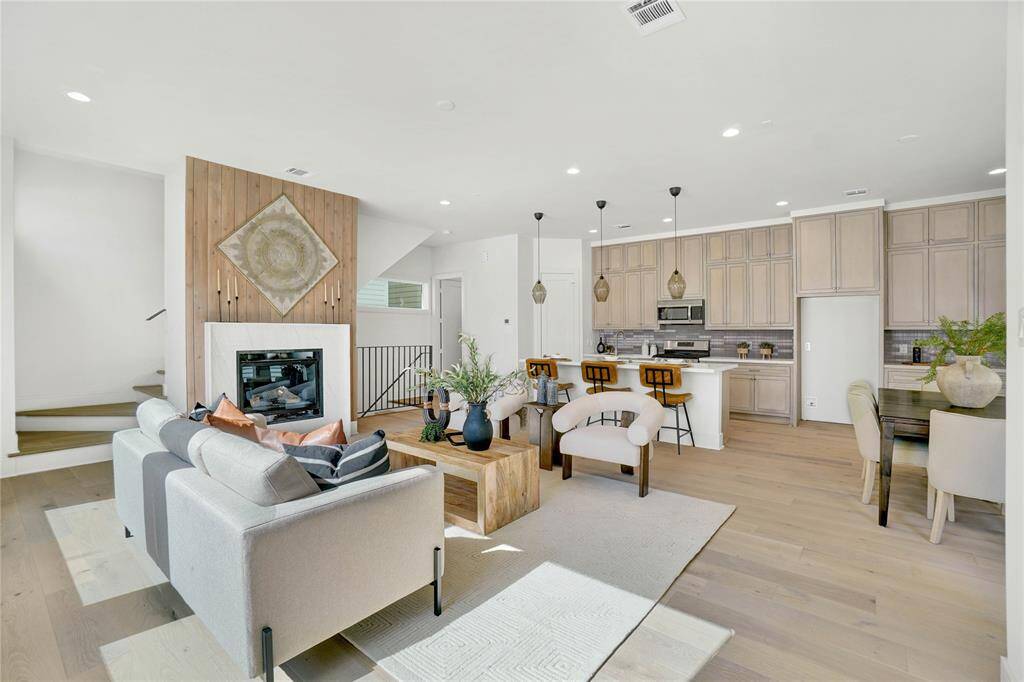 *Photos are from 5435 Darling*-This modern living space features an open layout with large windows, ample natural light, and a neutral color palette. The living room flows into a dining area and kitchen with contemporary lighting and sleek finishes, offering a welcoming and stylish environment.