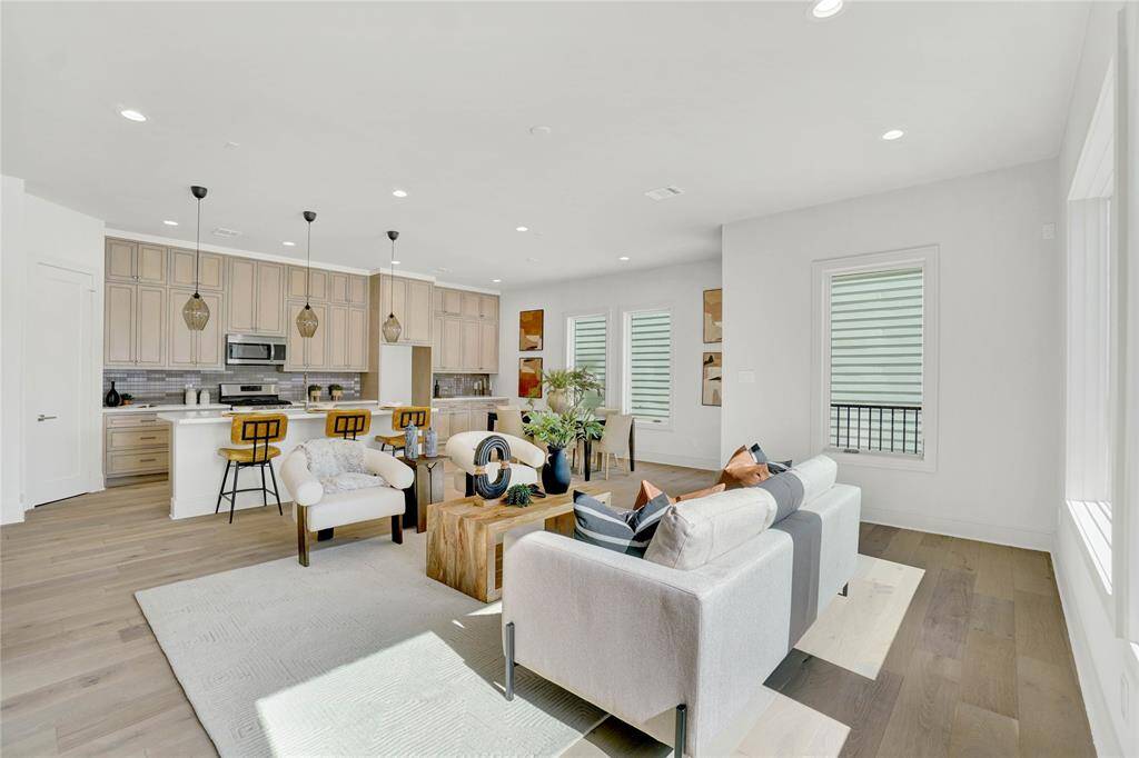 *Photos are from 5435 Darling*-This modern living space features an open layout with large windows, ample natural light, and a neutral color palette. The living room flows into a dining area and kitchen with contemporary lighting and sleek finishes, offering a welcoming and stylish environment.