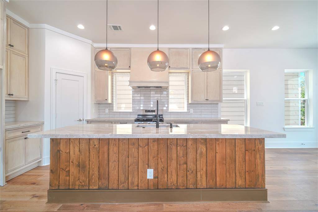 This modern living space features an open layout with large windows, ample natural light, and a neutral color palette. The living room flows into a dining area and kitchen with contemporary lighting and sleek finishes, offering a welcoming and stylish environment.