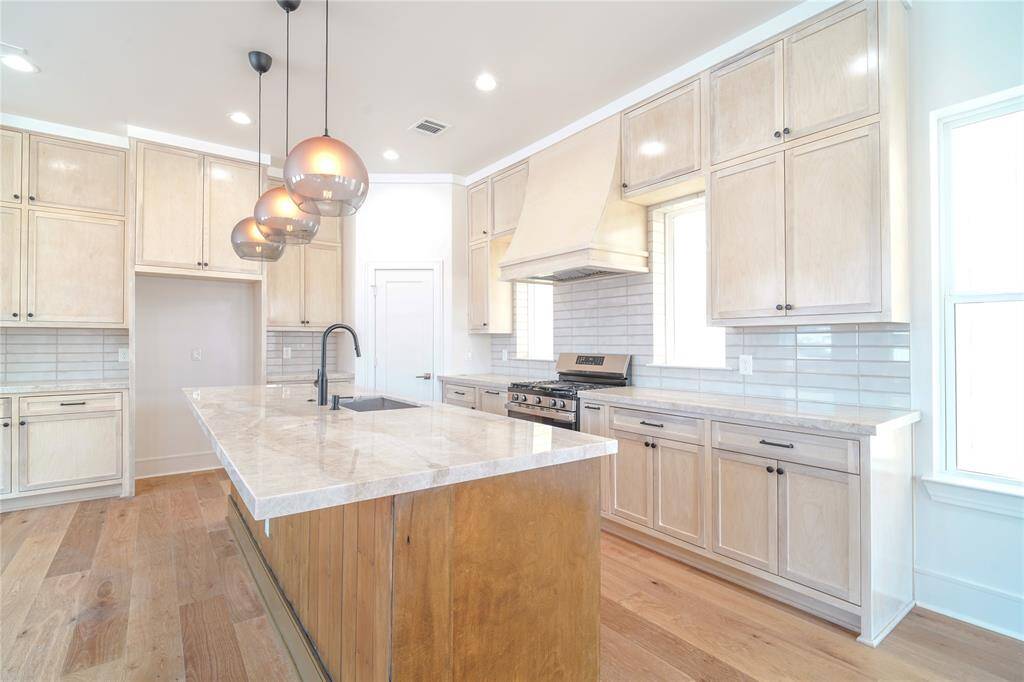 This modern living space features an open layout with large windows, ample natural light, and a neutral color palette. The living room flows into a dining area and kitchen with contemporary lighting and sleek finishes, offering a welcoming and stylish environment.