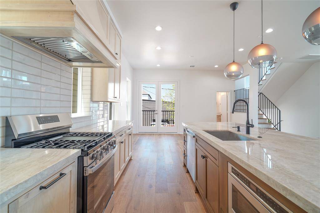 This modern living space features an open layout with large windows, ample natural light, and a neutral color palette. The living room flows into a dining area and kitchen with contemporary lighting and sleek finishes, offering a welcoming and stylish environment.