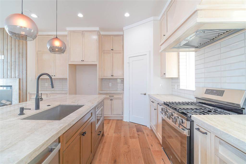 This modern living space features an open layout with large windows, ample natural light, and a neutral color palette. The living room flows into a dining area and kitchen with contemporary lighting and sleek finishes, offering a welcoming and stylish environment.
