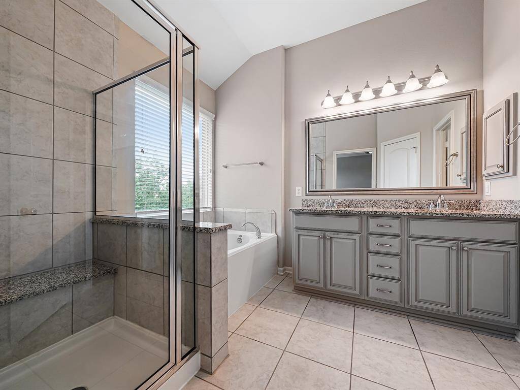 The primary ensuite bathroom is a luxurious retreat, featuring dual sinks, an extended vanity with ample storage, and an elegant framed mirror.