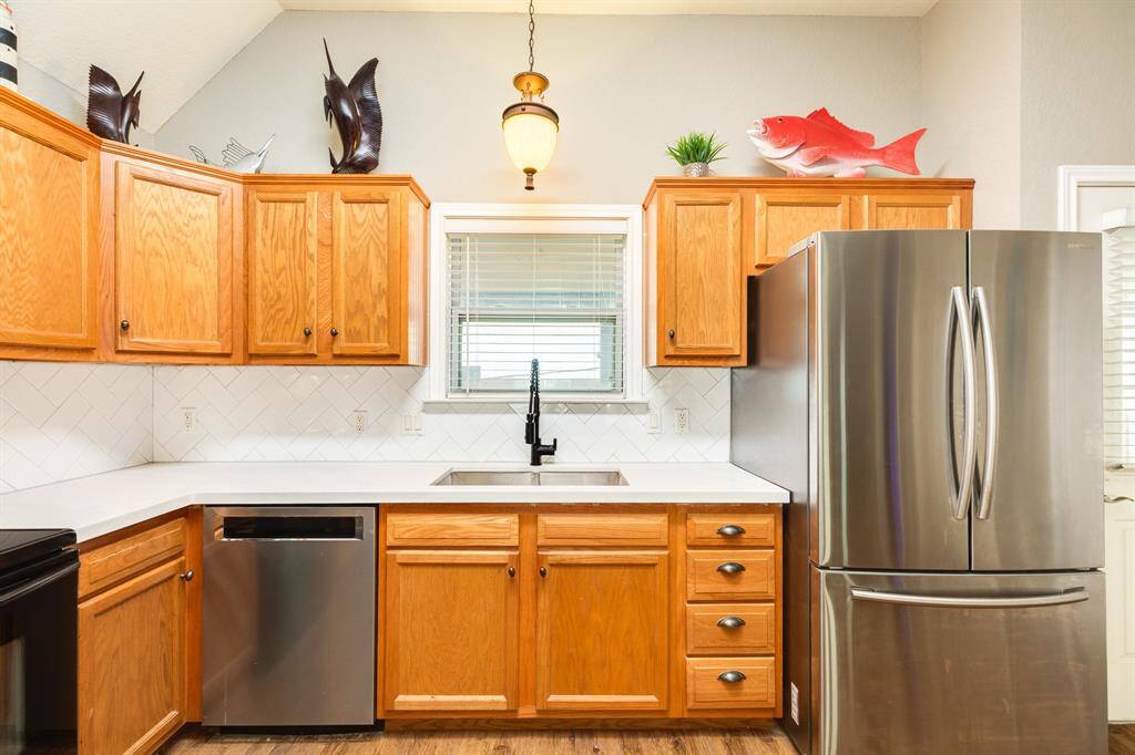 This kitchen features window over the sink for sunset and bay side views,  and a modern faucet. Accents include decorative fish and a hanging light fixture, with a window for natural light.