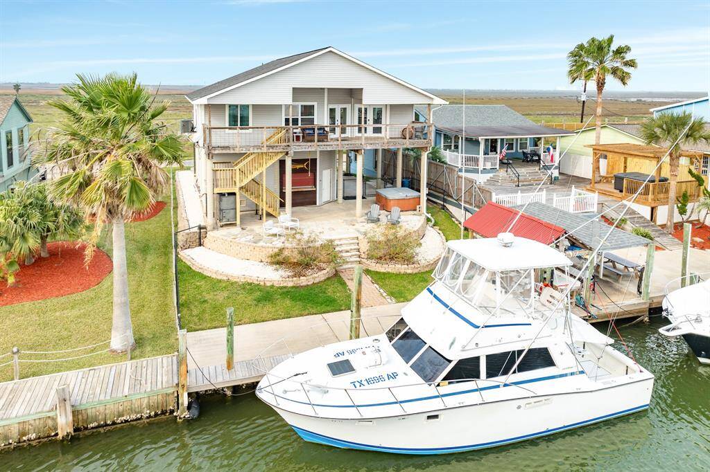 This canalfront home features  a spacious deck, ground floor entertainment area, dock access, and a boat slip. The exterior includes palm trees and a well-maintained lawn, perfect for enjoying coastal living.