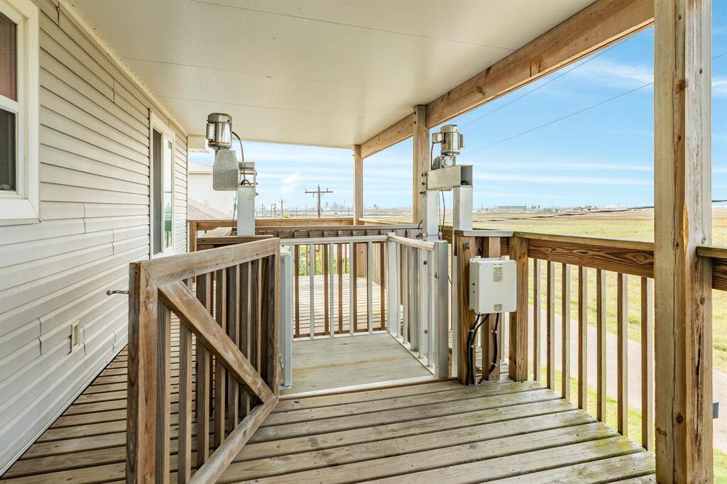 This photo showcases the back covered wooden deck with railing, providing expansive bay views. Ideal for relaxing and enjoying outdoor scenery while enjoy the convenience of a lift.