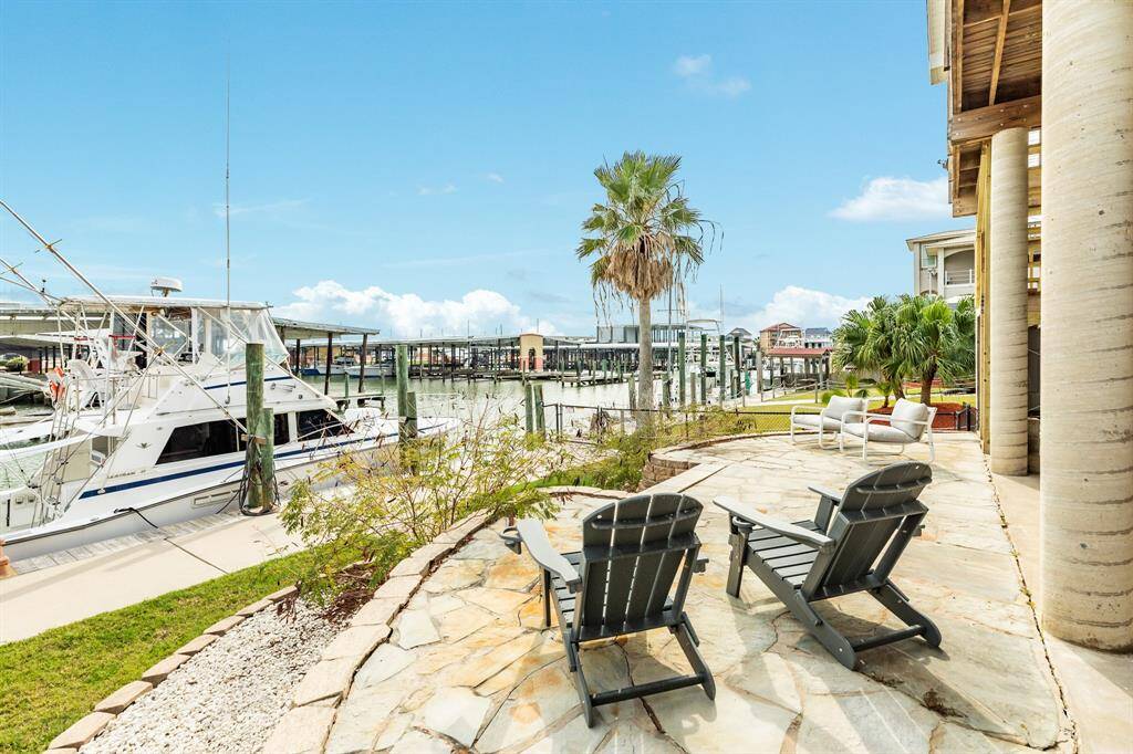 This waterfront property features a spacious stoned patio with comfortable seating, perfect for relaxing and enjoying views of the marina. The setting is enhanced by palm trees and easy dock access, ideal for boating enthusiasts.