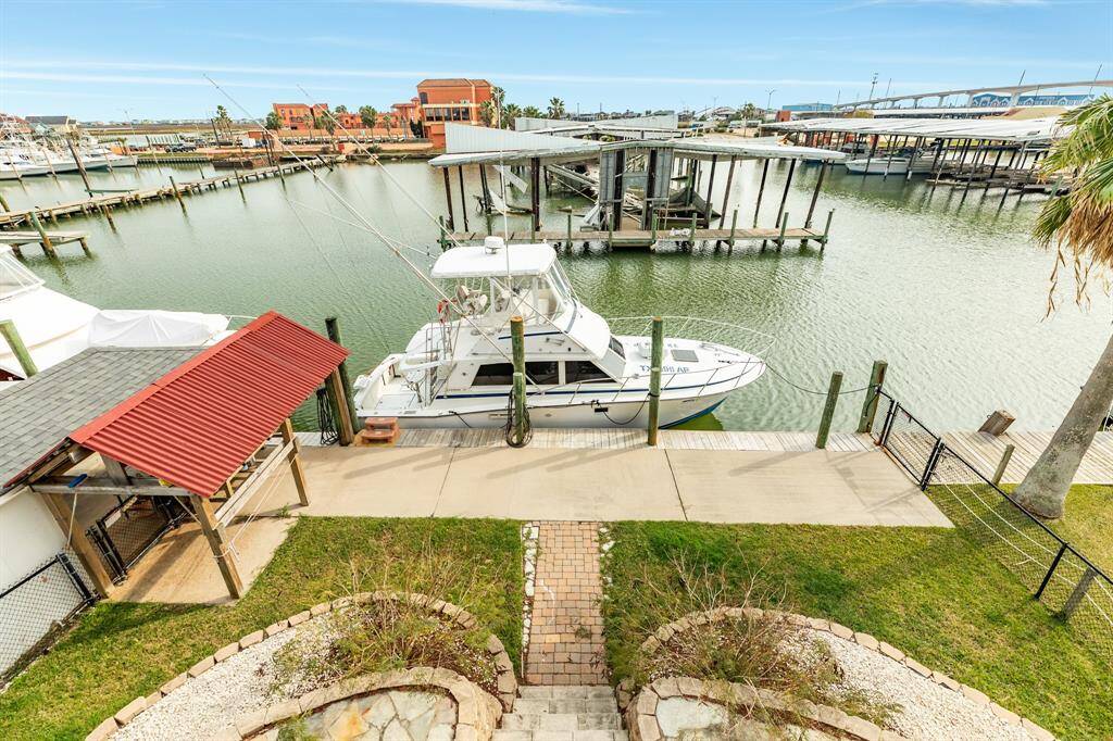 56 Marlin Deck View showcases a waterfront property with  boat access. The area features a well-maintained lawn, paved walkway, and a covered fishing station, offering scenic water views and convenient boating opportunities.