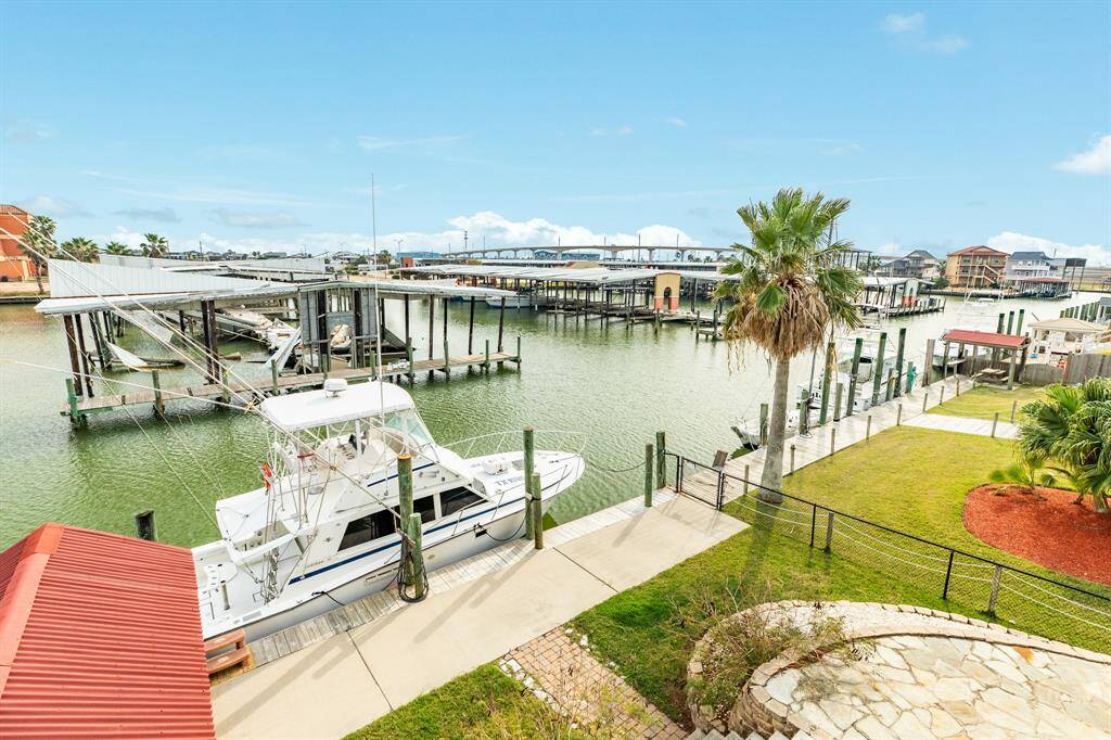 This photo showcases a waterfront property featuring a boat slip and scenic views of the marina. The area is well-maintained with a palm tree and lush lawn, perfect for boating enthusiasts and those seeking a serene waterside lifestyle.