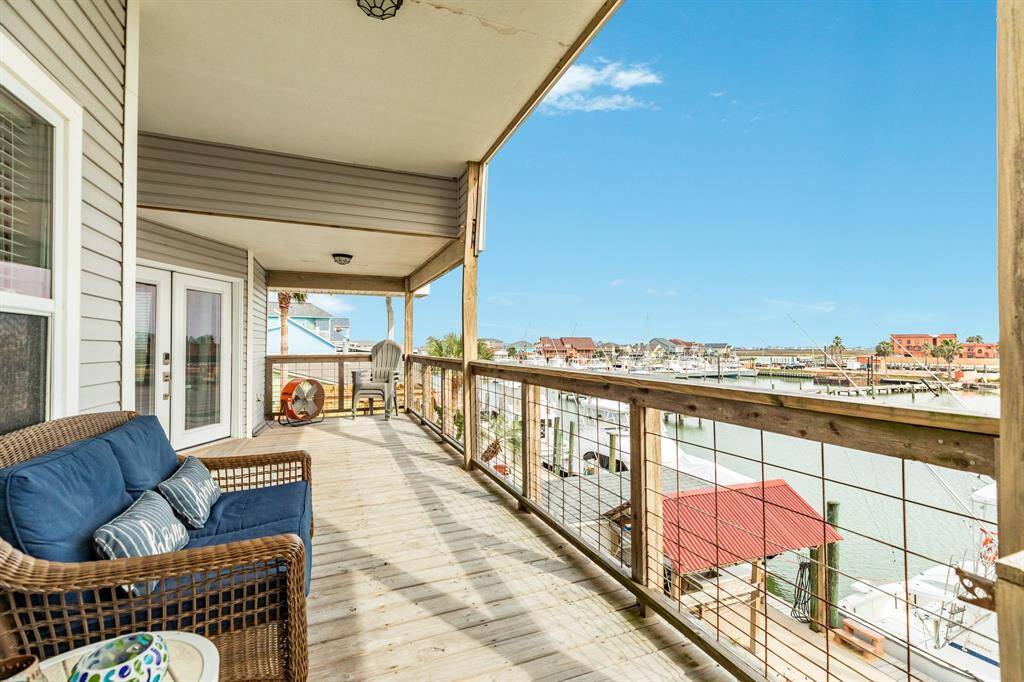 This photo showcases a spacious wooden deck with comfortable seating, overlooking a marina. The view includes boats docked along the water and nearby buildings. It's an inviting space for relaxation and enjoying waterfront living.