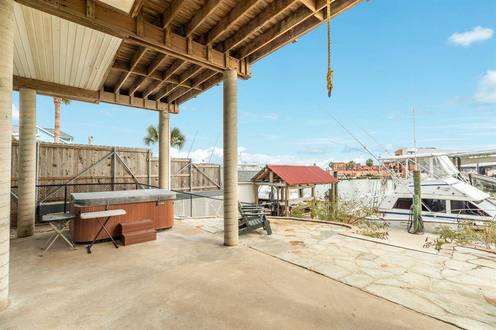 This photo showcases a waterfront patio area with a covered space featuring a hot tub, outdoor seating, and a view of the marina. It offers a relaxing and inviting setting, perfect for enjoying coastal living.