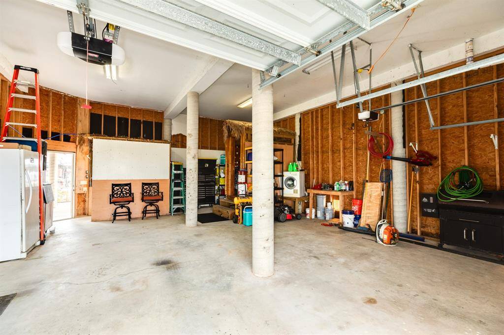 2 car garage features ample storage, and workspace. It includes a utility area with a washer/dryer, and various tools, making it ideal for projects and organization.