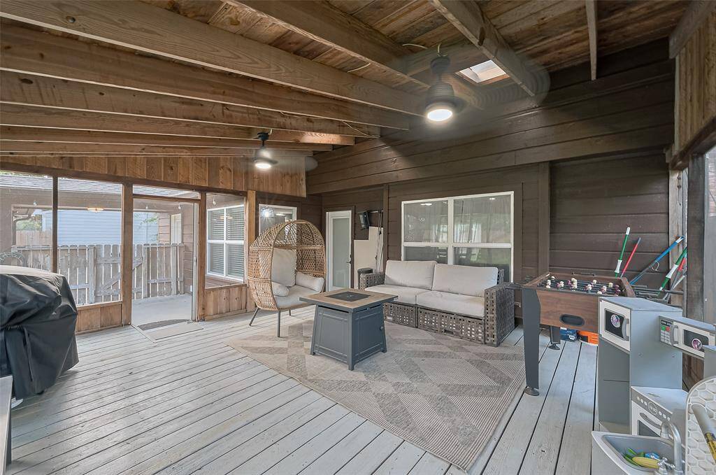 Enclosed screened patio with wooden beams and deck flooring, a perfect space for FUN! Natural light streams through screen windows