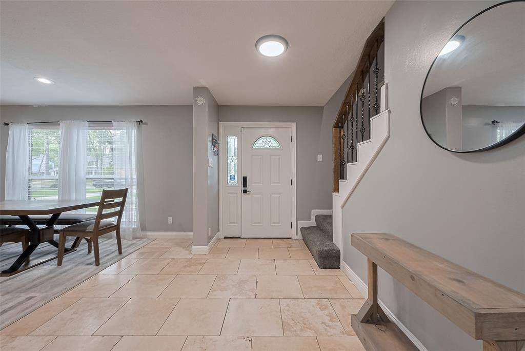 Bright and welcoming entryway with tile flooring, iron spindle staircase. The area shows how you can add your own touch with a console and art or shelving…so much potential for that wall space off the family room! Also, adjacent is an awesome dining area with large windows, providing plenty of natural light, open windows to the front lawn