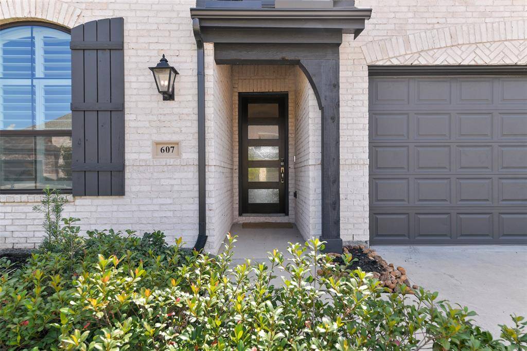 Manicured landscaping maintained by an in-ground sprinkler system lines the path to this inviting covered front porch with the juxtaposition of an old-world carriage light and a modern-style 8-foot door with a keyless electronic lock.