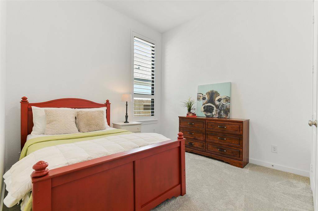The fourth and final bedroom in this home also offers a raised 11-foot ceiling, neutral paint, plush carpet, a side-facing window shaded by plantation shutters, and a double-door closet.