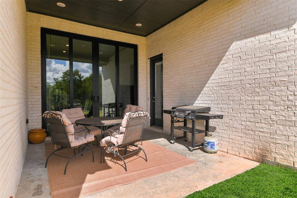 Step outdoors from the main living area onto this ample covered patio with recessed lights, a concrete floor, and views of the compact backyard with a wrought iron fence and peaceful park-like greenspace beyond.