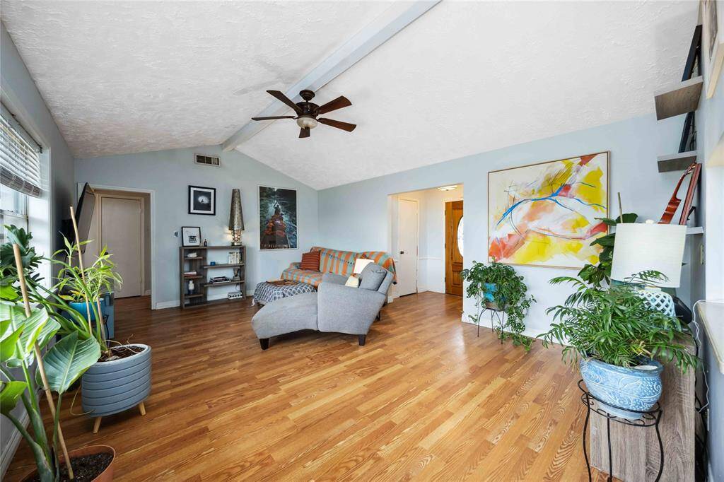 The living room rests under a vaulted ceiling and boasts ample natural light.